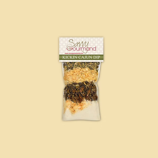 Packaged seasoning mix for 'Kickin' Cajun Dip' by Savvy Gourmand on a beige background