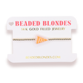 A gold beaded bracelet with a small orange triangular charm reading 'VOLS', displayed on a white branded card labeled 'BEADED BLONDES' and '14 K GOLD FILLED JEWELRY'.