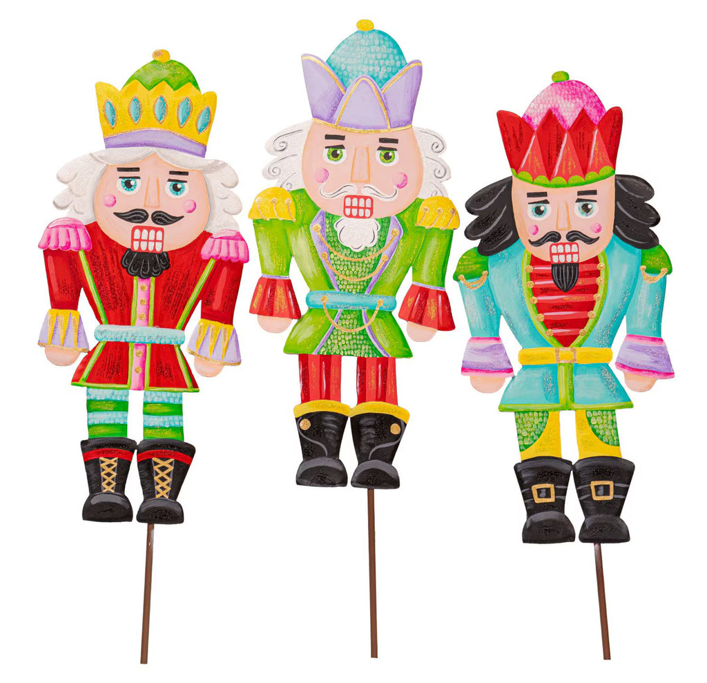 Three colorful nutcracker figurines on sticks with decorative hats and outfits.
