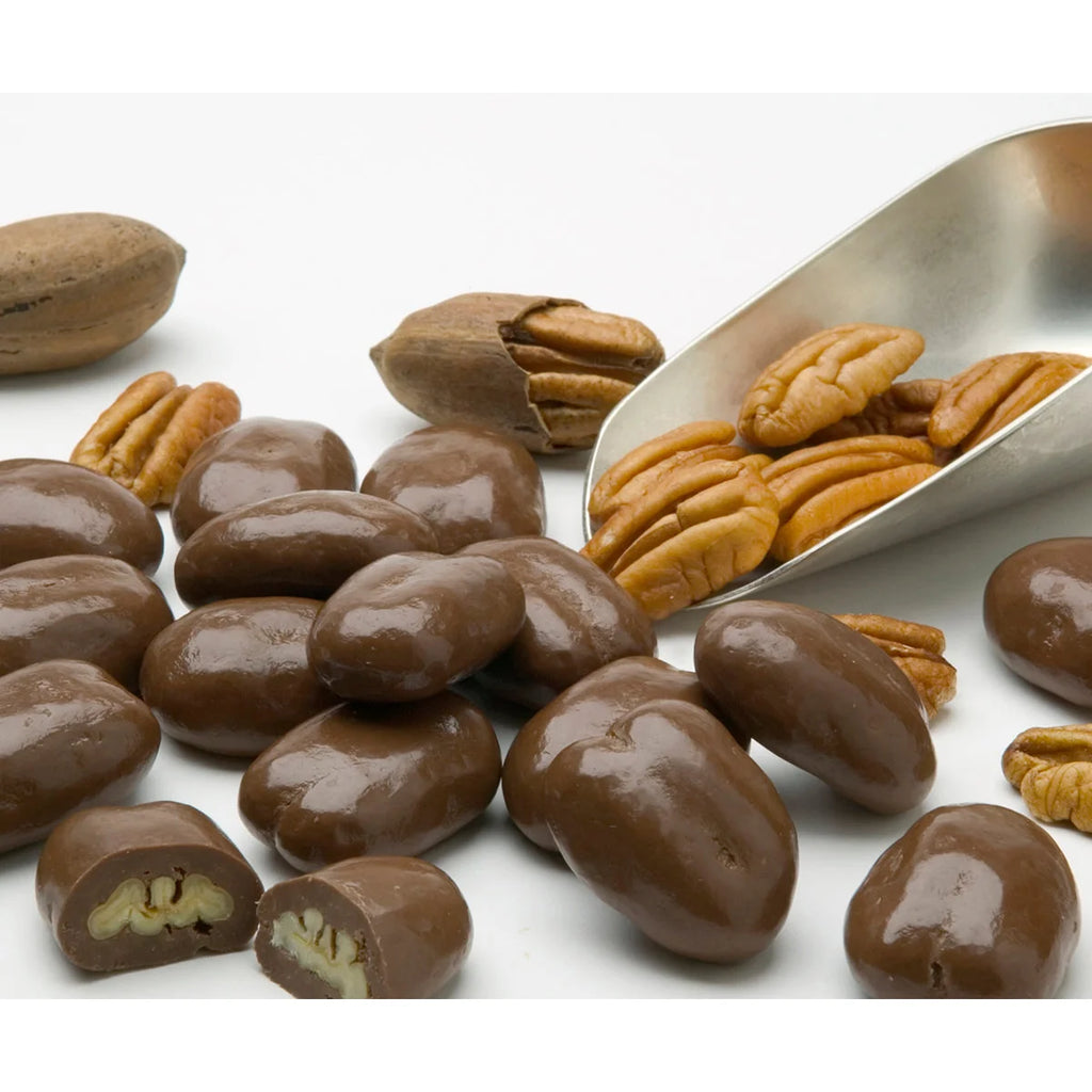 Chocolate-covered pecans with a metal scoop on a white background