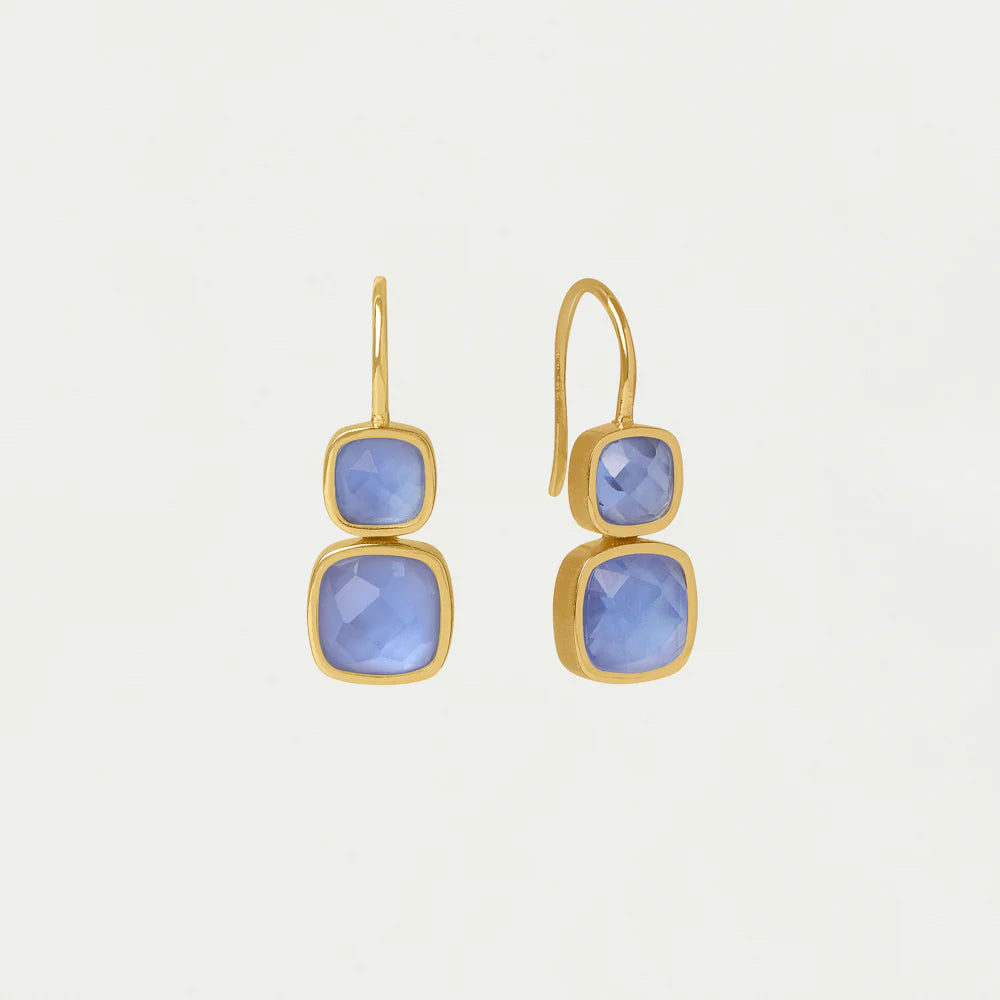 Gold earrings with blue gemstones on a light gray background