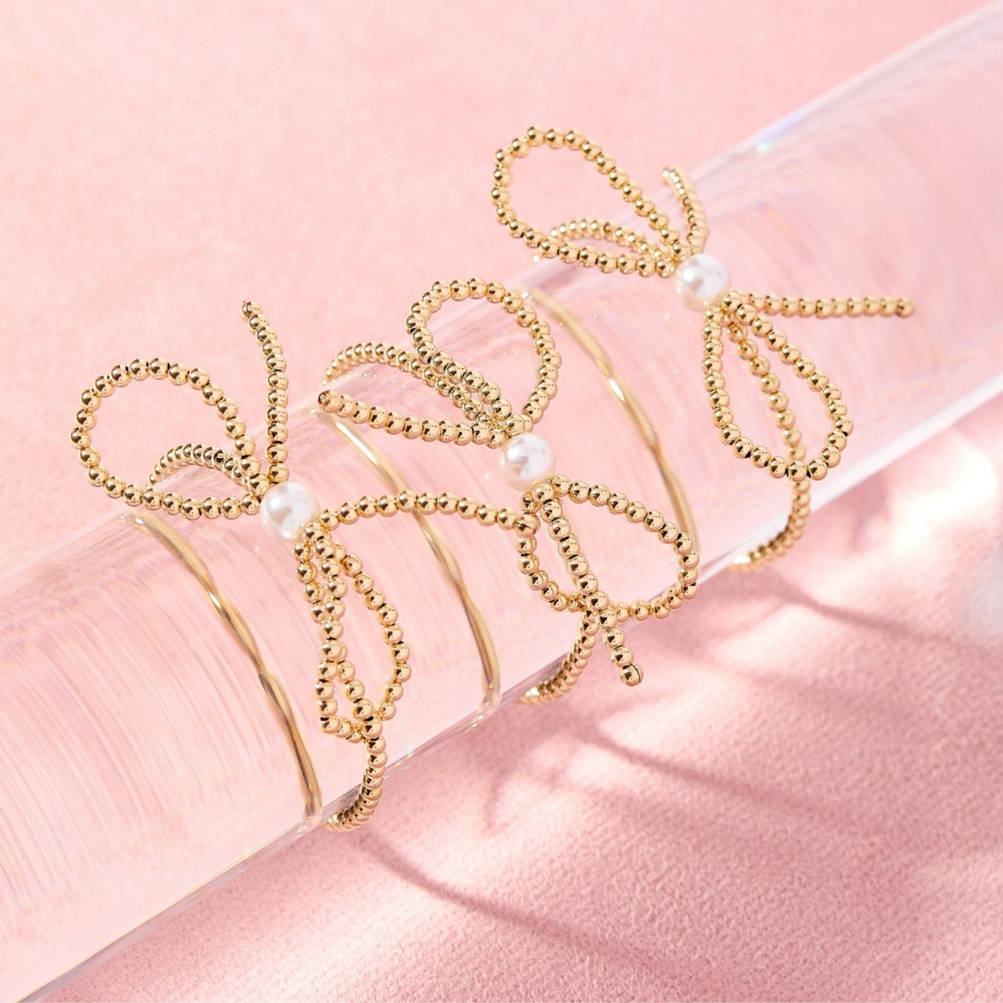 Gold headbands with pearl accents on a pink background