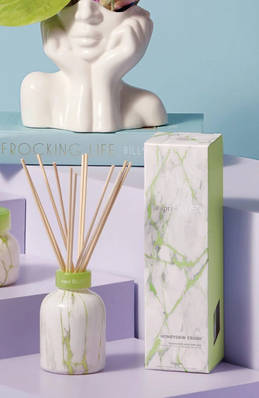 Marble-patterned candles and diffusers with a decorative head vase on a pastel background