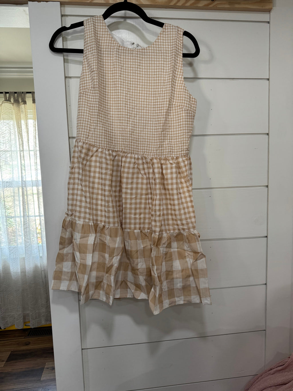 Checkered dress on a hanger against a white wall