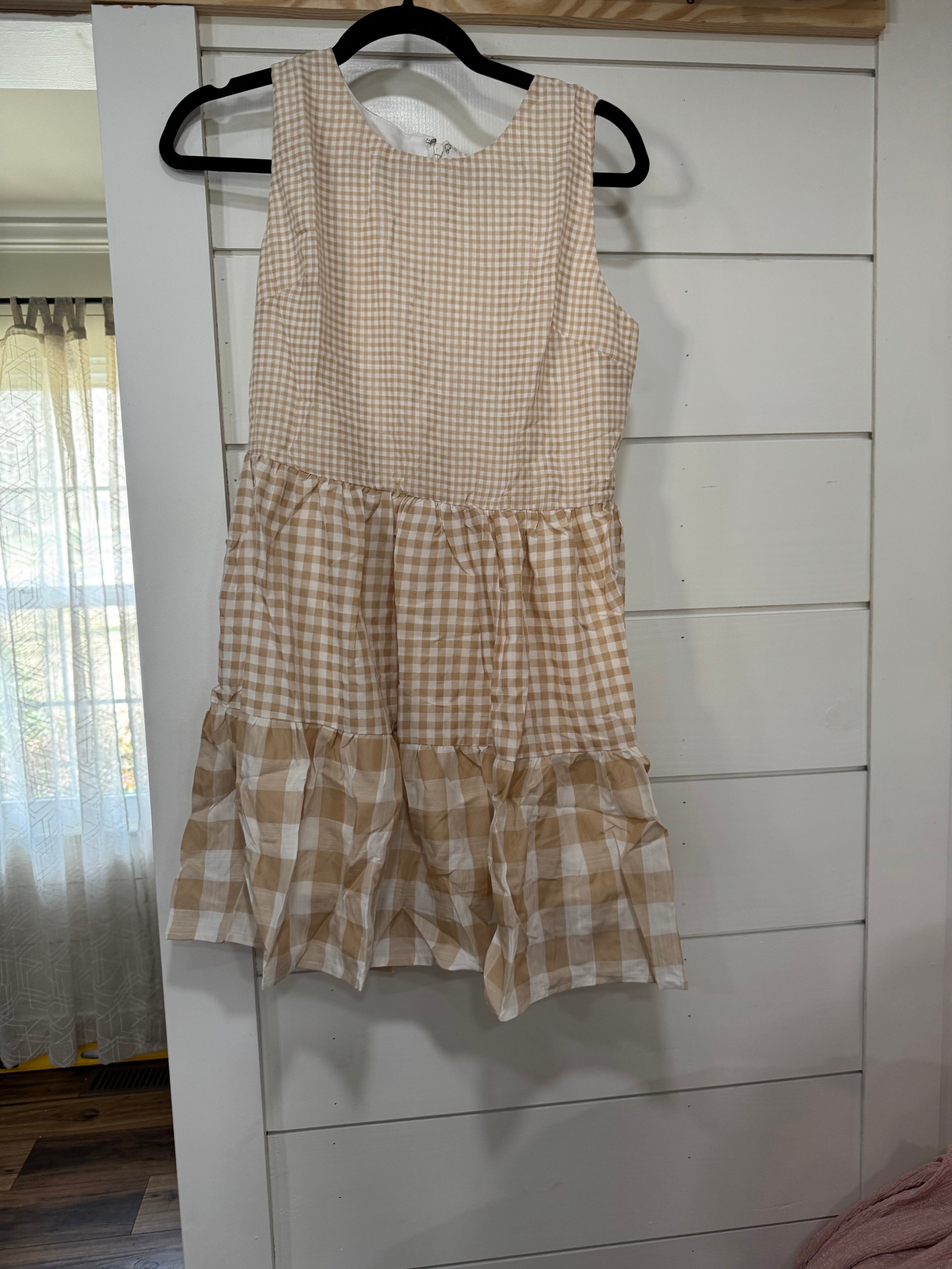 Checkered dress on a hanger against a white wall