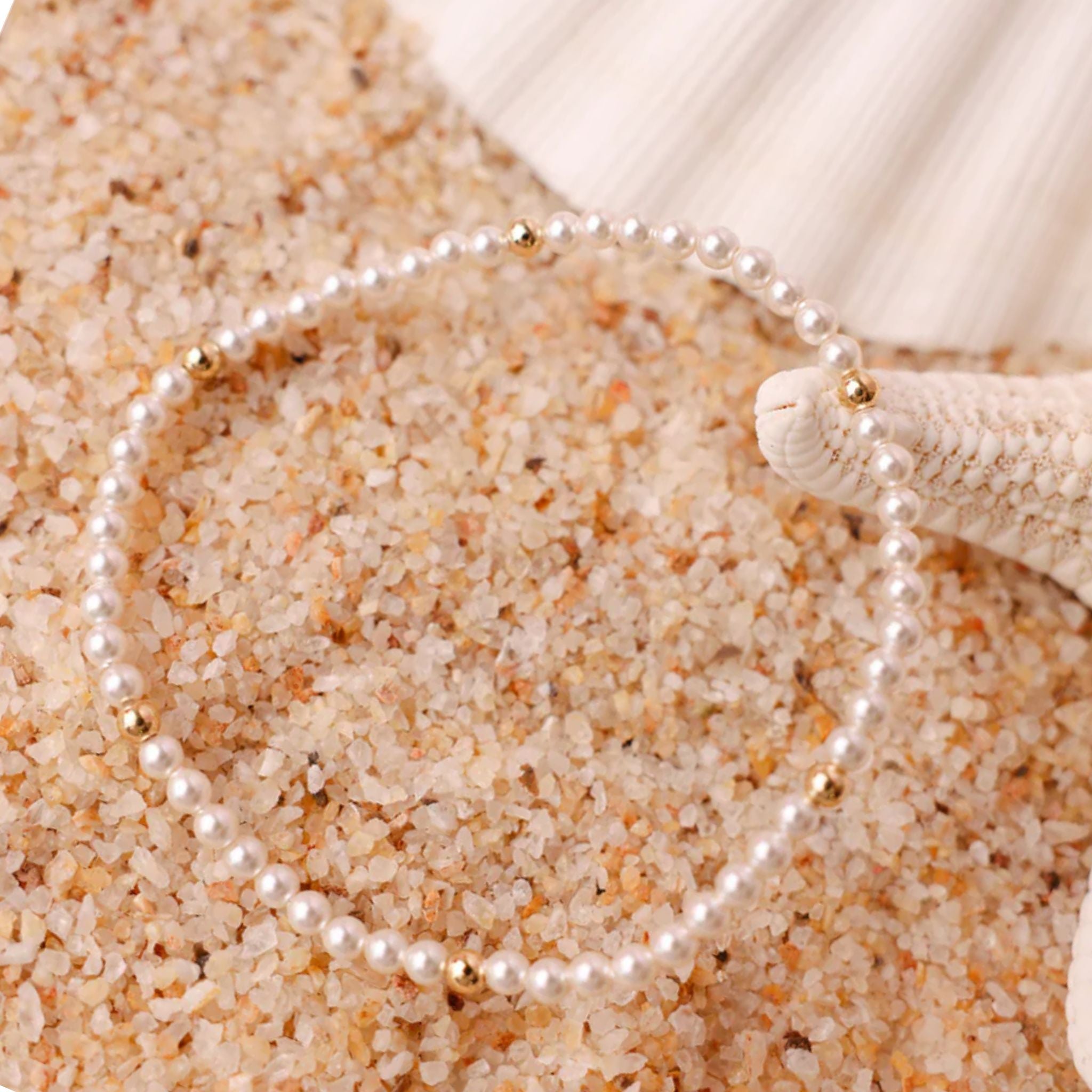 Pearl Bracelet on sand with a shell in the background