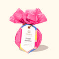 Pink bath bomb with a 'Happy Birthday' tag on a white background
