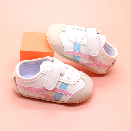 Off white infant tennis shoes with pink and blue accents and velcro closure for baby girls