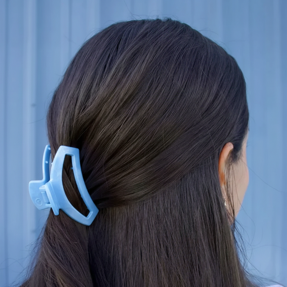 Person with a blue hair clip in their dark hair against a light blue background