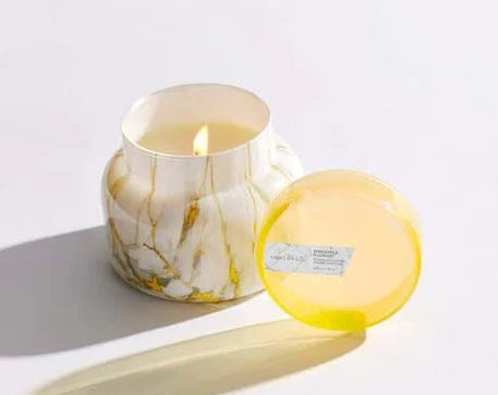 Marble-patterned candles with colorful lids on a white surface