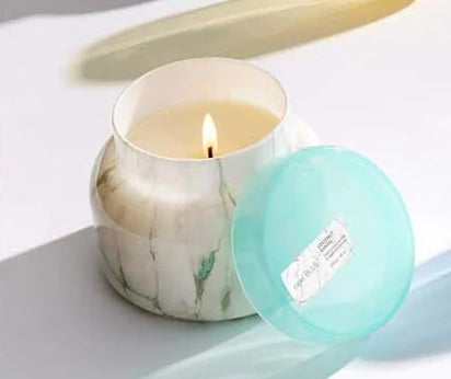 Marble-patterned candles with colorful lids on a white surface
