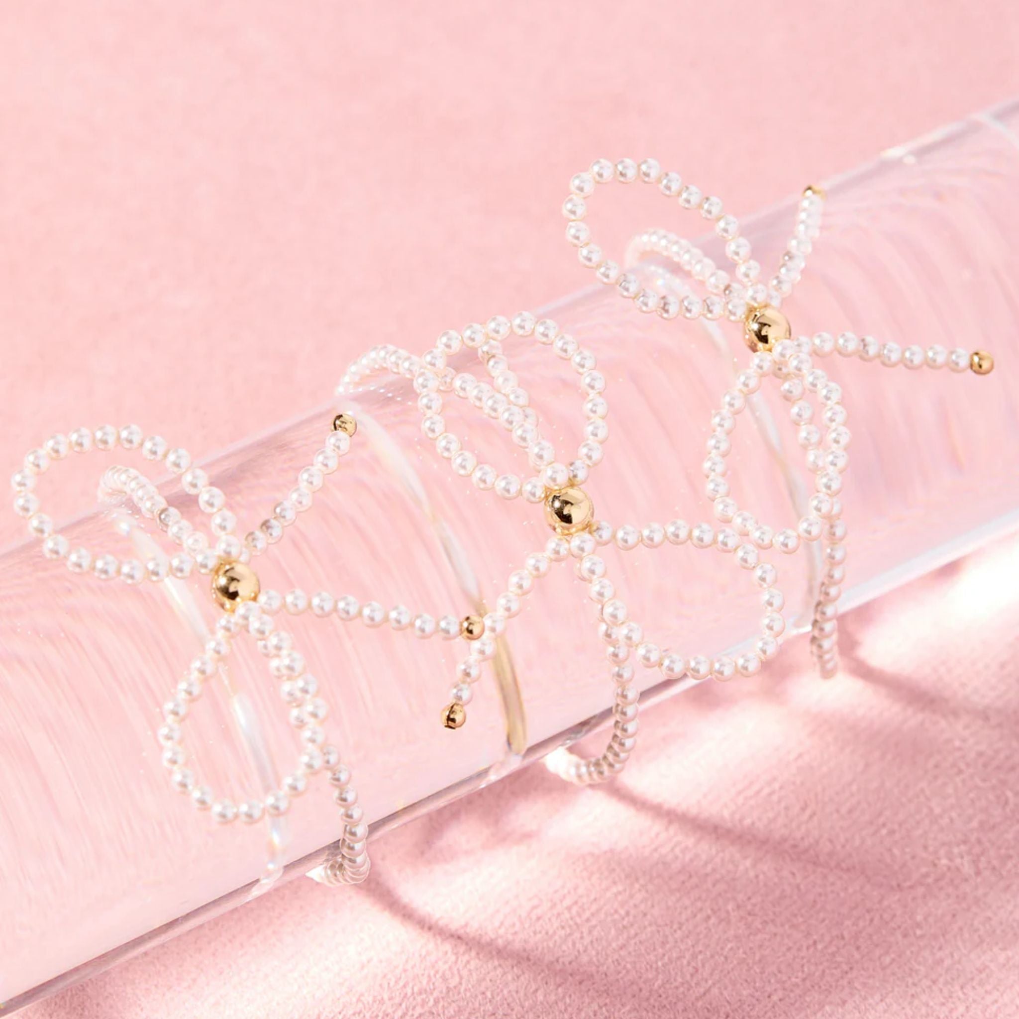 Pearl necklaces with gold accents on a pink satin surface