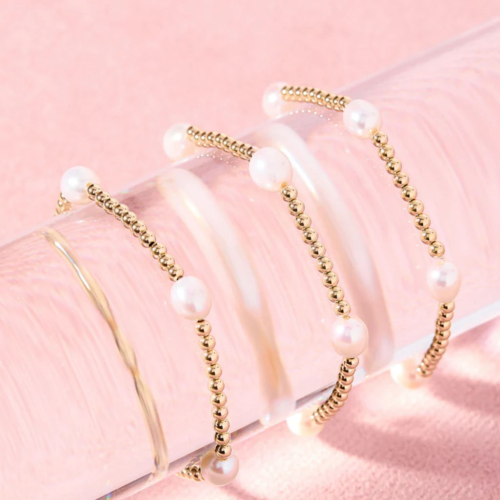 Set of pearl and gold beaded hairbands on a pink background