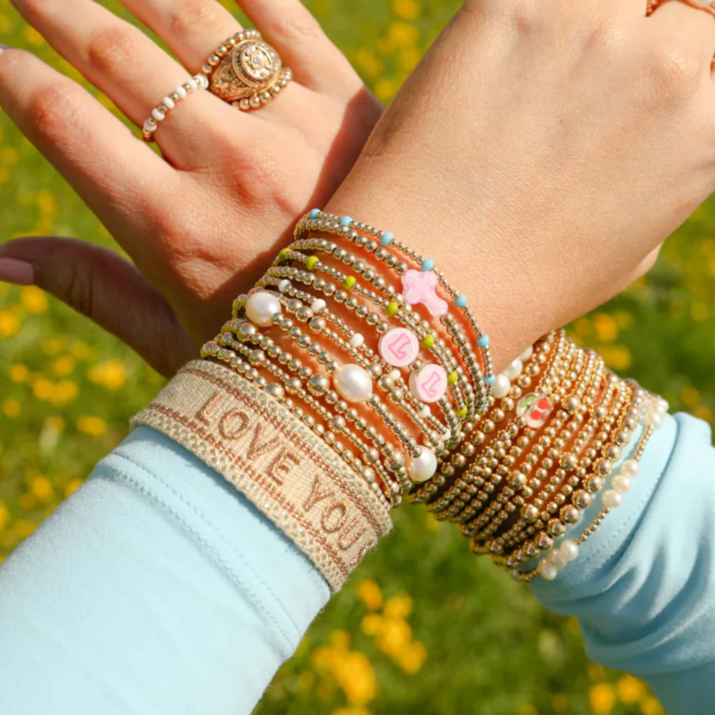 Close-up of a hand wearing multiple bracelets with a blurred green background